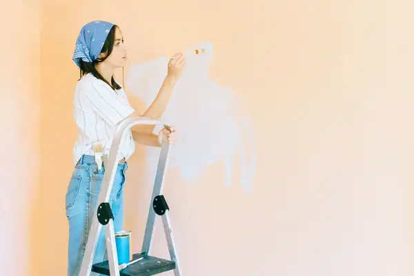 Interior painting in Anchorage: painter on a stepladder rolling a wall